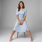 Professional e-commerce fashion photography — create a realistic product-on-model shot using the provided reference images. You are given 2 images: image 1 = product reference, image 2 = model reference. Dress the model from the second image in the product from the first image. The product must be physically placed on the model's body — worn naturally with correct fit, draping, and proportions as it would appear in real life. The product is the hero of the shot and must be clearly visible, prominently displ
